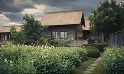 some bushes grass flowers and a house
