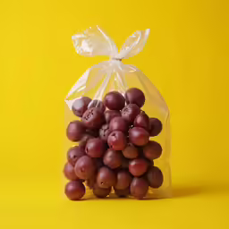 a bag of grapes sitting on a yellow surface