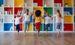 five children jumping in front of colorful shelves