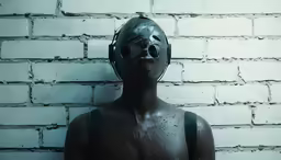 a man is in a mask and is in front of a brick wall