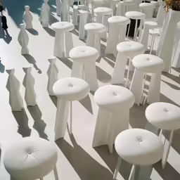 a bunch of white stools and tables in a room