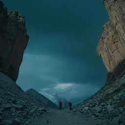 a man and woman walking into the light between two rocks