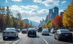 cars travelling on a road with trees and buildings in the background
