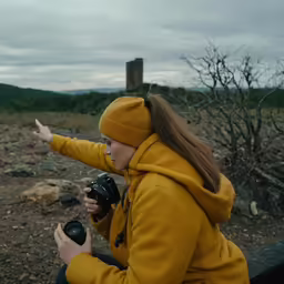 a woman holds her camera in one hand and points at something