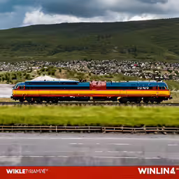 a very large train on a steel track,a train traveling down tracks past a lush green hillside