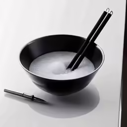 two black spoons in a black bowl and a pen on top