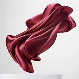 a sculpture in red flowing satines on a table