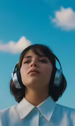 a woman wearing headphones is in a blue sky