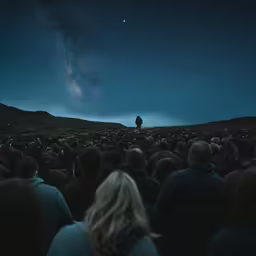 people looking up at the stars and a man in black standing on top