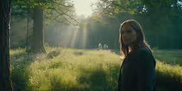 a beautiful blond haired woman standing in front of a tree