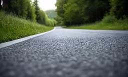 asphalt road with grass and trees at end