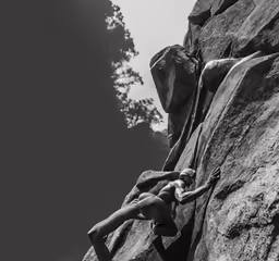 a man climbing up the side of a large rock