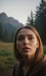 woman standing outside in grassy field near mountains
