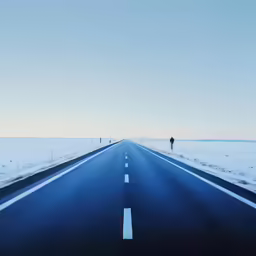 a person walking across the empty road in winter