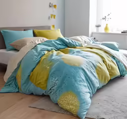 a bedroom with large bed with yellow and blue sheets