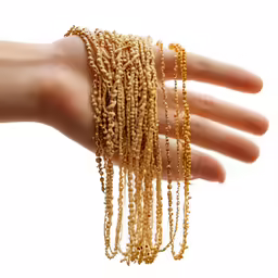 a close - up image of a hand holding some gold beaded necklaces