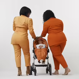 two women pushing an orange baby carriage