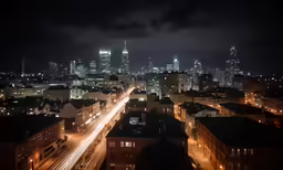 city lights over buildings in the distance, with skyscrapers in the background