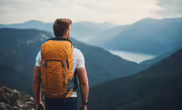 a man with backpack standing on top of a hill