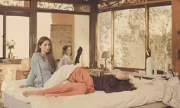 two women laying on the bed in a bedroom