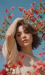a woman with short hair is standing beneath a flowering tree