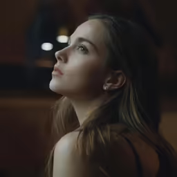 a woman with brown hair looking up to the sky