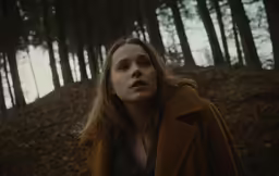 a woman standing in the woods, looking up