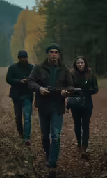 people walking in the woods with a gun in their hands