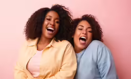 two young women laugh while they pose for the camera