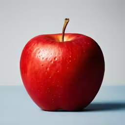 an apple with the stem still attached on a table