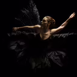 the ballerina in the black dress is playing with her skirt