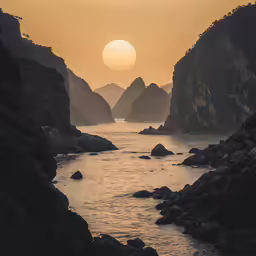 the sun setting on a very rocky and quiet bay