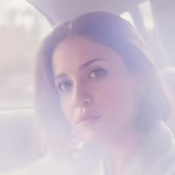 a woman is staring intently into the distance while sitting in a car