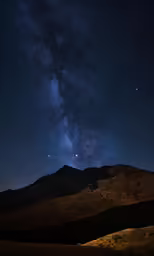 the night sky above mountains with stars above