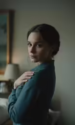 a beautiful woman standing by a window with a jacket on