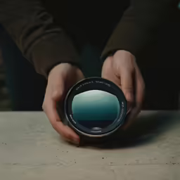 a person holding a camera lens with their hand