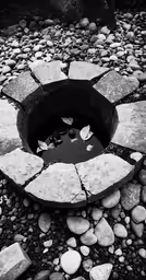 a black and white photo of a well in the rocks
