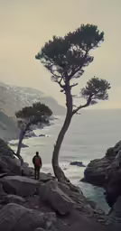 two people standing next to each other on a cliff by the ocean