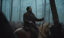 a man riding on the back of a horse next to a forest