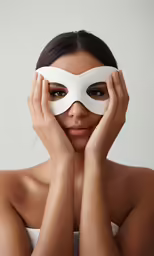 a woman with her hands to her face, with a white mask on