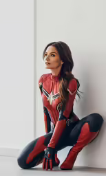 a woman in red and black standing next to a wall
