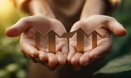 a woman holds up gold paper figures on her palms