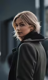a woman wearing a coat is standing next to a building