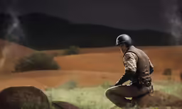police officer with helmet sitting on large rock in open field