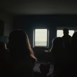 people gather in silhouette to watch the tv