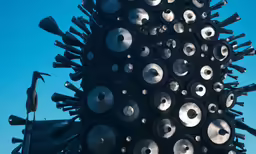 a tall metal sculpture with lots of round and pointed objects all around it