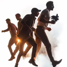 several men in silhouettes as they walk along with the camera