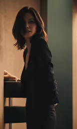 a woman leaning against the wall near a table