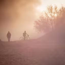 a couple of people walking their bikes down a hill