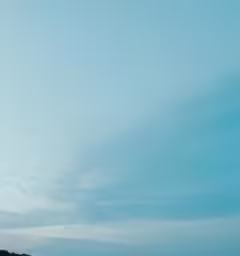 an airplane flies over the ocean with people watching